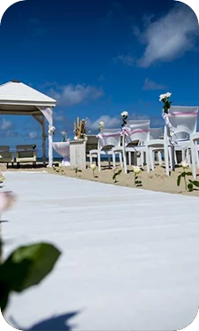 Een ceremonieopstelling met witte stoelen op het strand van een beachclub