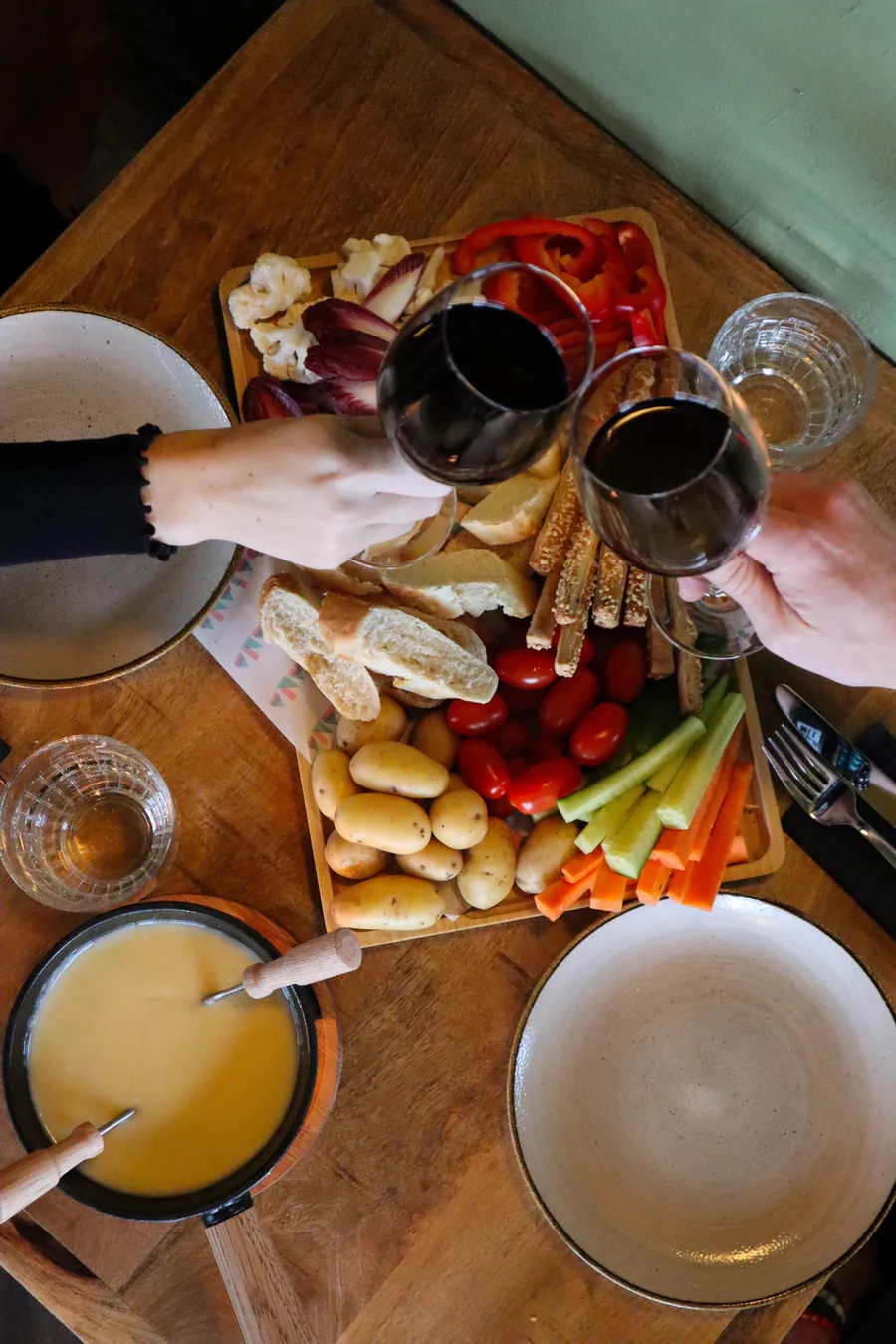 Een borrelplank met wijn, brood, groenten en dip op een houten tafel, van bovenaf gezien