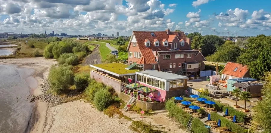 Luchtfoto van Baiana aan de Waal, met het terras, de strandbedden en de skyline van Nijmegen erachter
