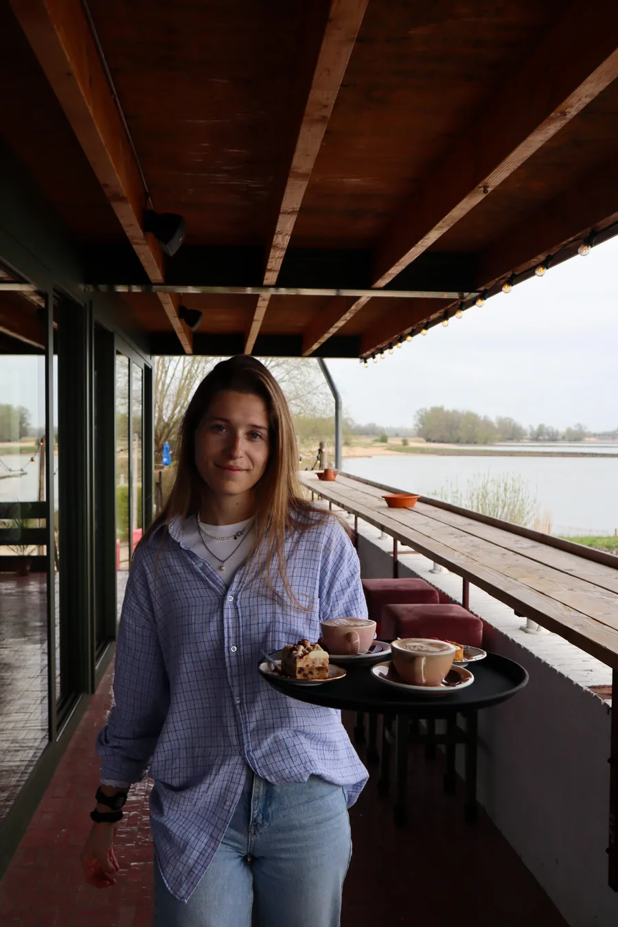 Een medewerker loopt met een dienblad langs de ramen die uitkijken op de Waal