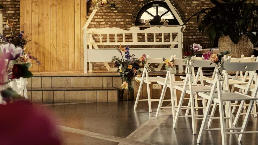 De Tuinkamer met witte klapstoelen en bloemen, klaar voor een ceremonie