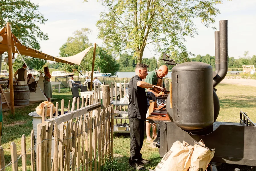 Twee mannen staan te barbecueën aan een houten hek in de tuin