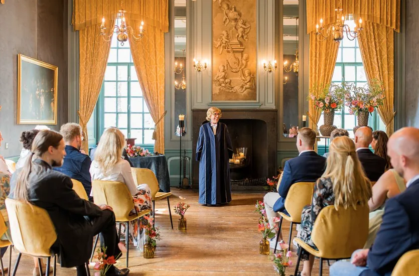 De trouwambtenaar staat voor de schouw in de zaal van Kasteel Wijenburg