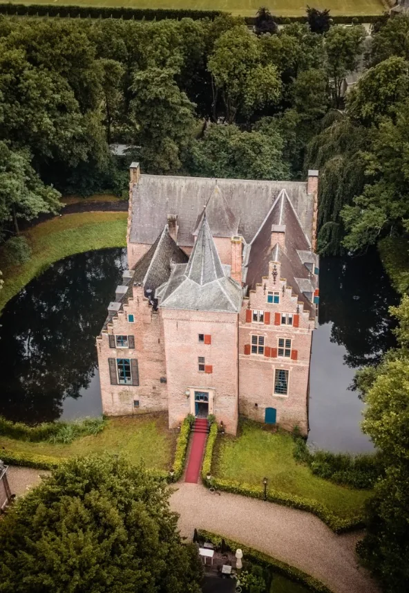 Kasteel Wijenburg van bovenaf, omringd door de gracht, met een rode loper naar de voordeur