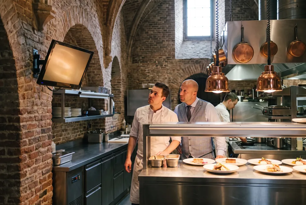 Johan Huisman en de chef kijken samen naar het scherm bij de doorgeef in de kasteelkeuken