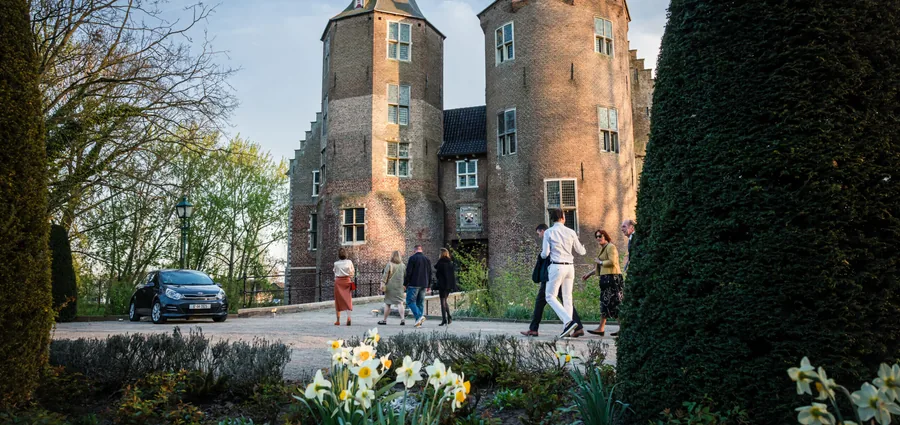 Kasteel Dussen met narcissen in de border en gasten op het pad ervoor