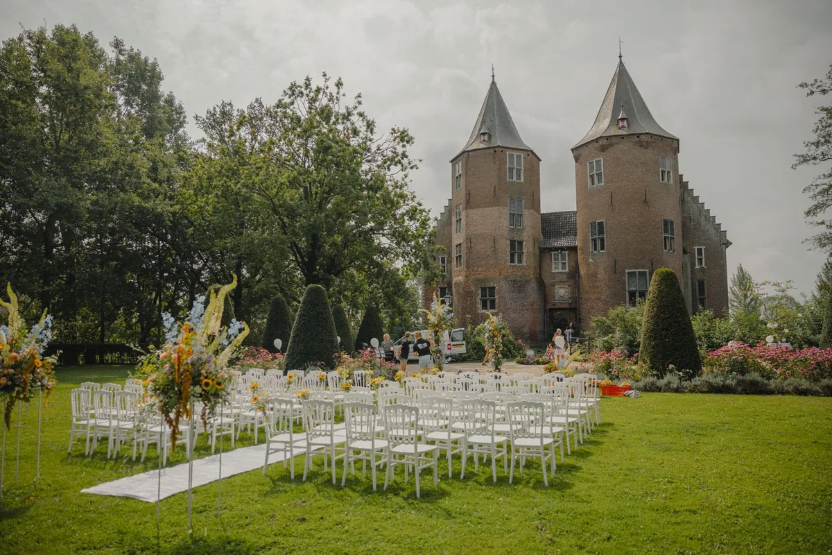 Rijen witte stoelen op het gazon voor Kasteel Dussen, klaar voor een ceremonie