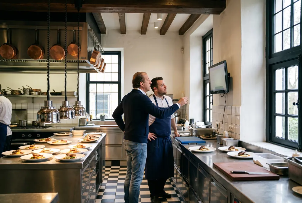 Jan-Willem en de kok kijken samen naar het scherm bij de doorgeef in de keuken van het slot
